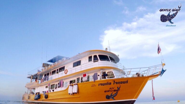 The MV Gentle Giant, a yellow and white liveaboard dive boat, anchored near the Similan Islands under a sunny sky.