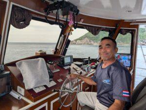 Captain Krai, the experienced pilot of the MV Gentle Giant, smiling confidently at the helm.