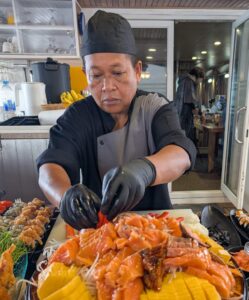 Head Chef Pom arranging a fresh salmon sashimi and sushi platter onboard the MV Aqua liveaboard.