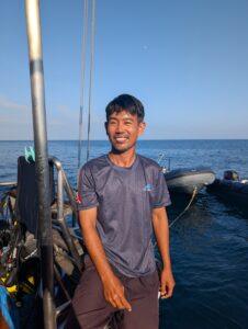 Deck hand Keng smiling on the dive deck of the MV Aqua, ready to provide Nitrox service.