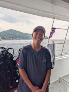 Nai, the stylish dinghy driver for MV Gentle Giant, smiling calmly while wearing a beige cap.